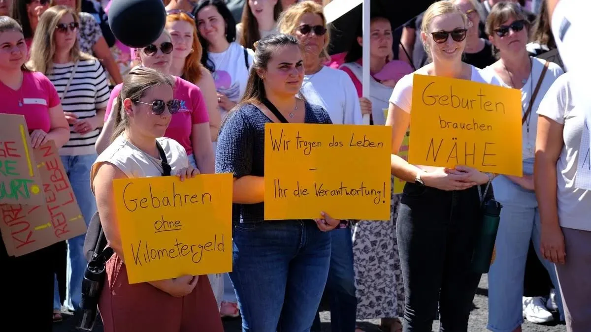 Frauen halten selbst gemalte Protestschilder gegen die Schließung der Geburtsstation hoch.
